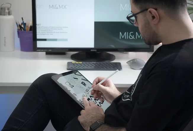 A designer working on a logo design on an Ipad with a pencil